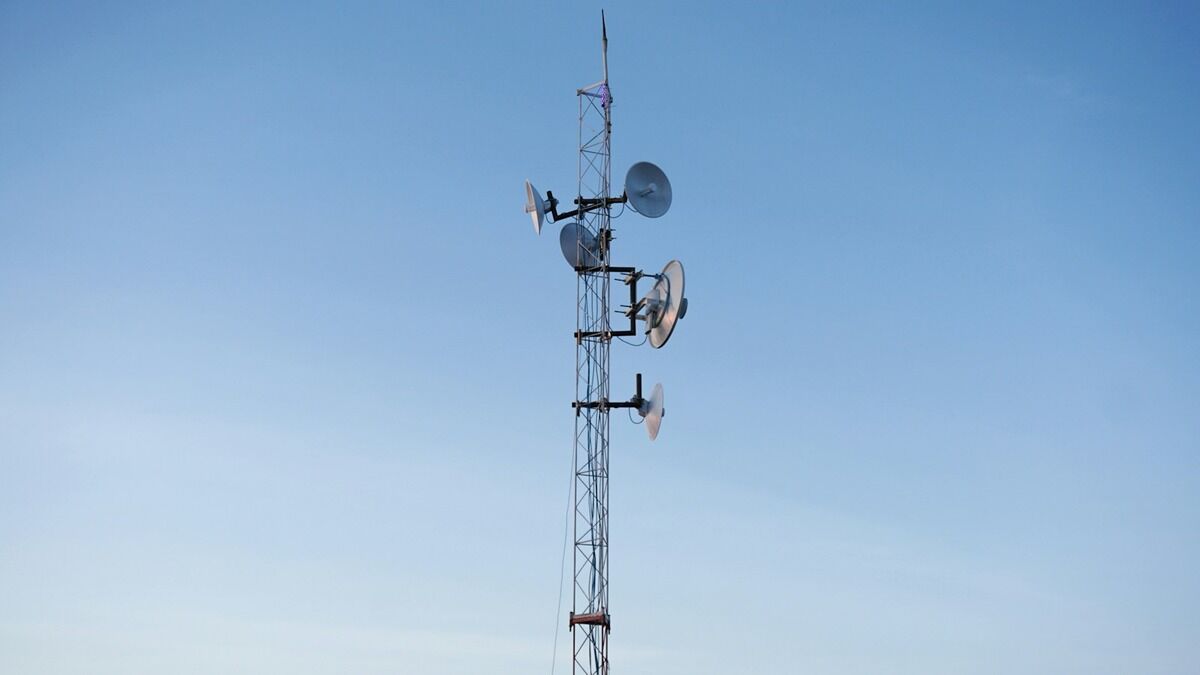 Antenne relais de téléphonie mobile avec trois panneaux sur fond de ciel bleu