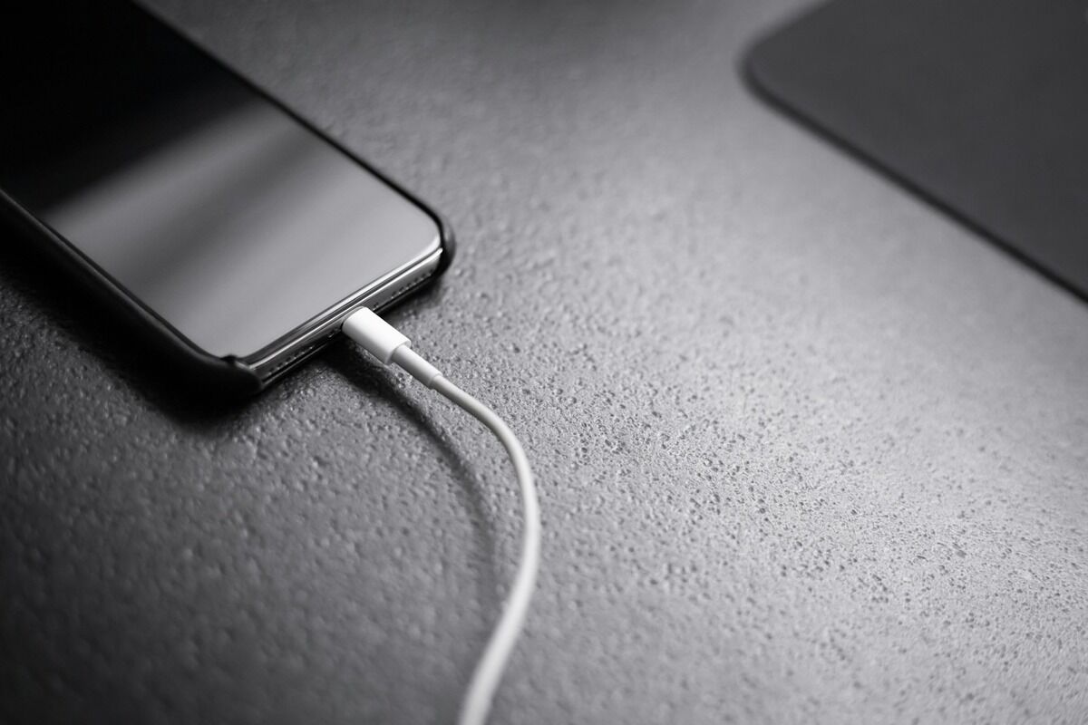 Smartphone noir posé à plat et branché à son câble de charge