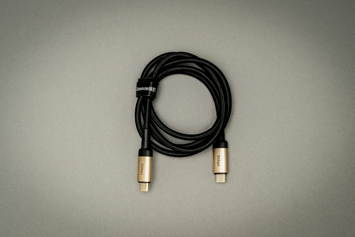 Câble USB-C noir enroulé, ses deux connecteurs métalliques posés l'un près de l'autre