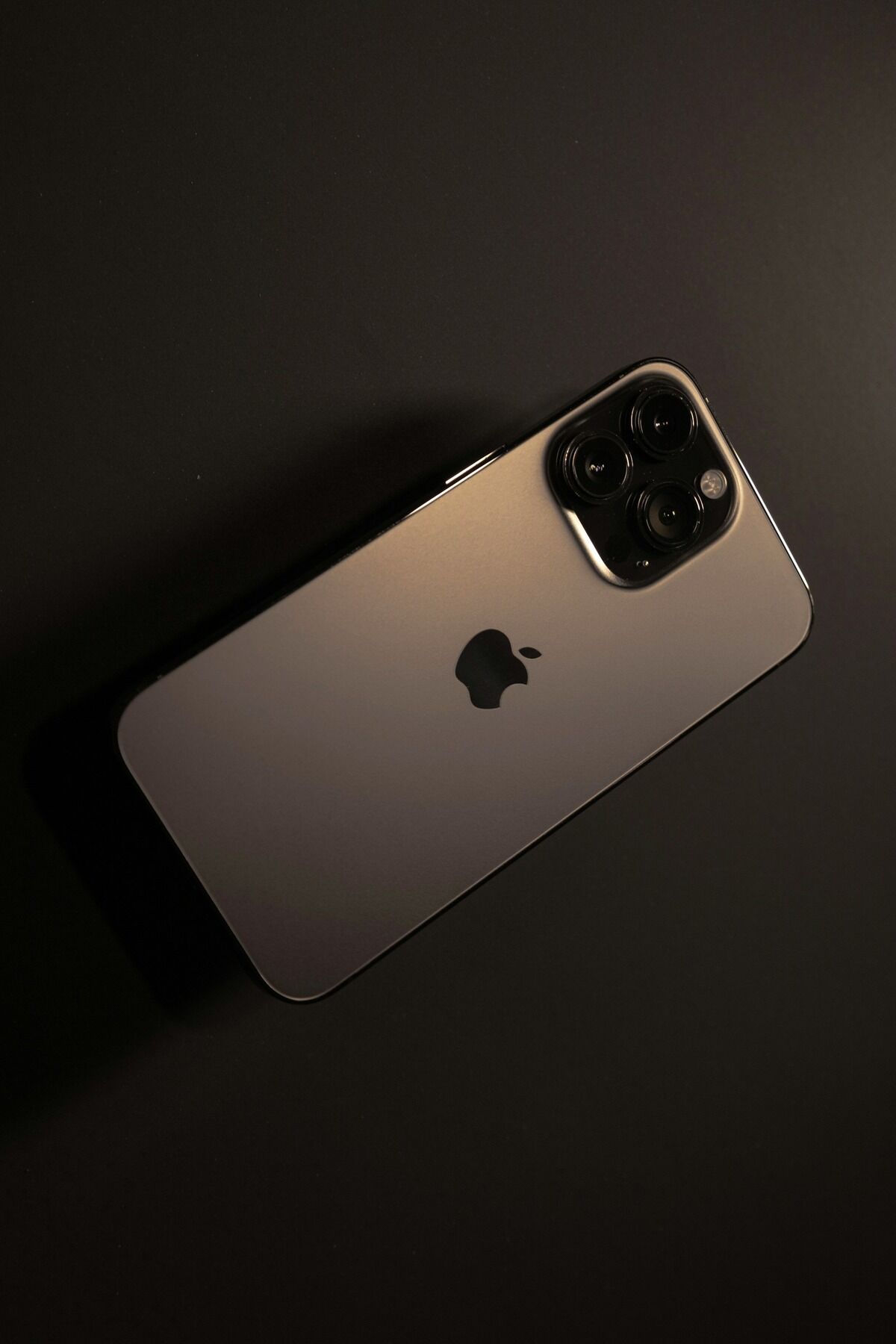 Gros plan sur le dos doré d'un iPhone Pro et son bloc photo à trois objectifs