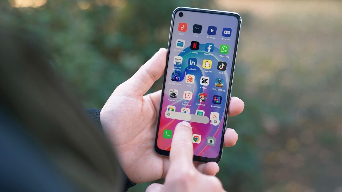 Doigt touchant l'écran d'accueil d'un smartphone Android rempli d'applications