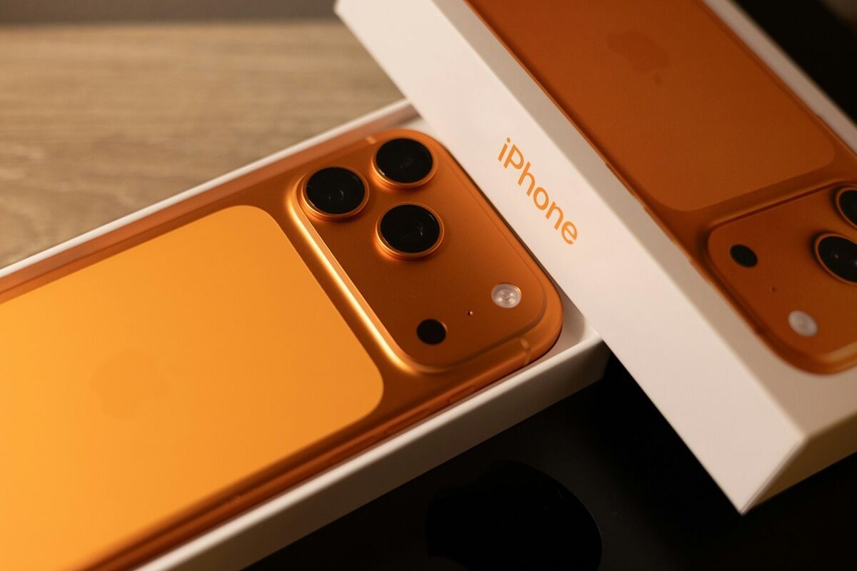 iPhone de couleur orange dans sa boîte d'origine, en cours de déballage