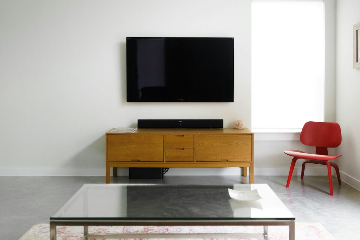 Téléviseur écran plat fixé au mur d'un salon moderne avec un fauteuil rouge