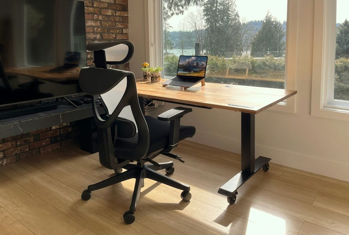 Poste de travail avec un bureau en bois et un fauteuil devant une fenêtre