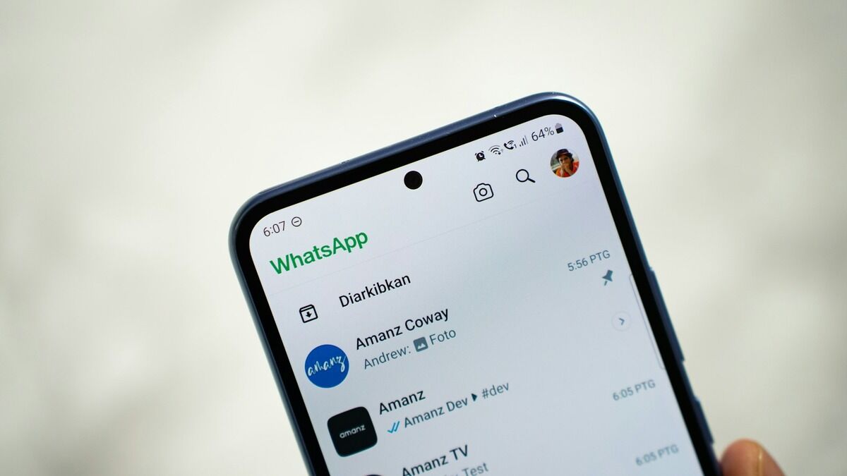 Main tenant un smartphone affichant la messagerie WhatsApp
